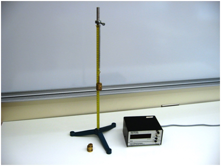 A stop clock and a vertical stand are placed on a table. A ruler runs along the vertical stand and is taped to it. At the top of the stand is an eye-bolt affixed horizontally. A mass holder with slotted masses is held vertically in the air by a spring attached to the eye-bolt. Additional, available slotted masses lie on the table.
