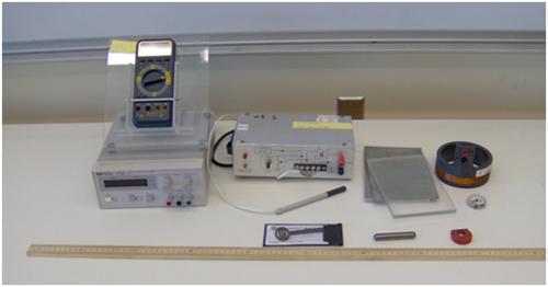 A photo of a power supply, the Hall probe apparatus, a multimeter, a circular coil, a meterstick, a horseshoe magnet, a cylindrical magnet, a steel sheet, a plastic block, an aluminum block, a compass, and a magnaprobe.